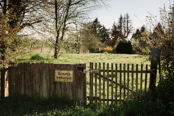 Fototapeta premium Hölzernes Gartentor mit Verbotsschild vor einem Garten im Frühling 
