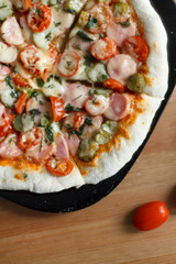 homemade pizza with sausage and cherry tomatoes close-up on a wooden table. culinary concept