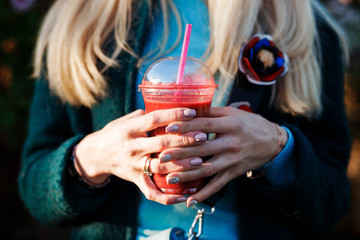 Close up view of the woman's hands holding smoothie.