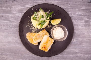 Cod fillet fried, served with mashed potatoes, grated cheese and cream sauce with chopped greens
