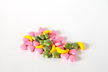 colored baby pills in the shape of stars of bananas hearts scattered on a white background