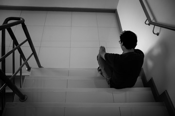 Depressed man sitting on stair of residence building. Sad man, Cry, drama, lonely and unhappy concept.