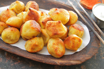 
fried ravioli on a wooden plate and served on a marble table with sauce and spices.