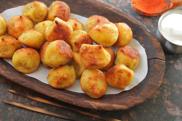 
fried ravioli on a wooden plate and served on a marble table with sauce and spices.