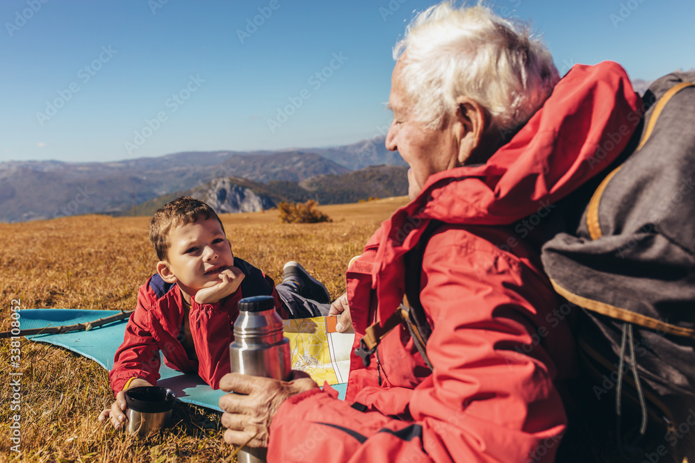 Wall mural Boy camping with grandfather in autumn.