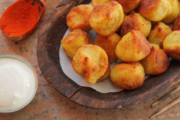 
fried ravioli on a wooden plate and served on a marble table with sauce and spices.