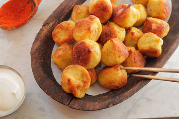 
fried ravioli on a wooden plate and served on a marble table with sauce and spices.