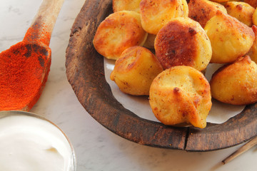 
fried ravioli on a wooden plate and served on a marble table with sauce and spices.
