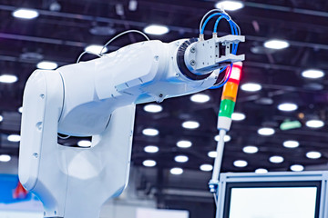 The robot arm is white. Hand of an industrial robot in the background of the production of lighting...