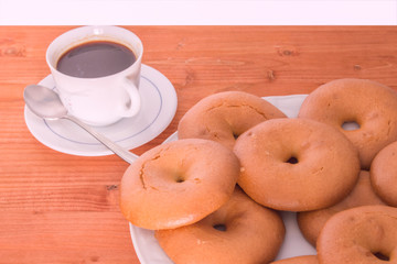 plate with bagel and coffee cup isolated on wooden table