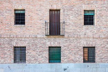 brick facade with five windows a balcony in a building in Madrid. Spain