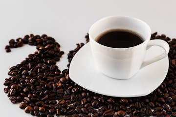 White cup with freshly poured coffee Close-up with a saucer and coffee beans around on a white background. Great background for a cafe or restaurant menu, signboard