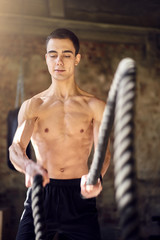 Fototapeta na wymiar Sportsman in training with ropes against background of brick wall