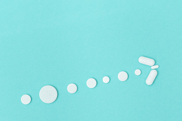 Pharmaceutical medicine pills, capsule lie on blue surfacein form arrow, virus distribution. Symbol Increase in number of cases in population. Copy space.
