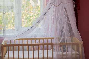 Fototapeta na wymiar baby cradle by the window,arrangement of the baby room before the baby is born