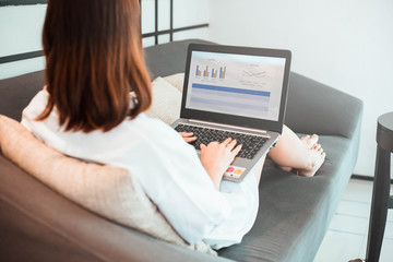 Fototapeta premium young woman working on laptop computer while sitting at the living room. work from home concept