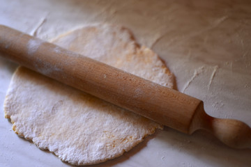 Rolling pin and dough on the table, a homemade food preparation