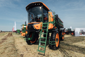 orange tractor sprayer in a field at an agricultural trade show in summer