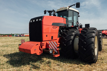 Obraz premium red tractor in a field at an agricultural exhibition in summer