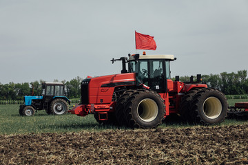 Fototapeta premium red tractor with large wheels in the field during tests during the exhibition