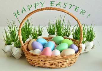 basket with colorful Easter eggs with green grass.Text HAPPY EASTER Holidays breakfast concept with copy space. Easter greeting card template. Homemade pasques.Easter sweets on white background.
