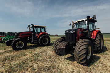 two red tractors in a field in summer during an agricultural exhibition