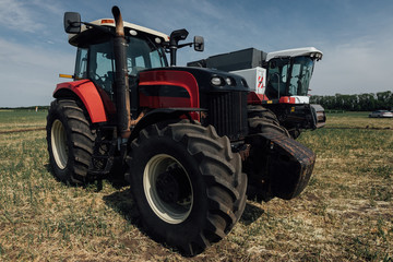 Obraz premium red tractor with large wheels in the field during tests during the exhibition