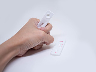 Woman holds in her hand positive pregnancy HCG test on white background. Closeup.