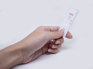 Woman holds in her hand positive pregnancy HCG test on white background. Closeup.