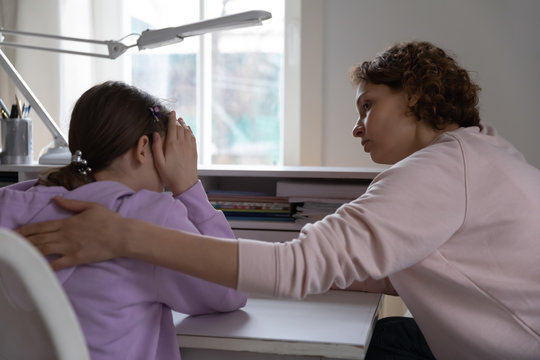 Worried Young Mother Talking Comforting Upset Teen Daughter Helping With Problem Or Apologizing At Home. Caring Parent Mum Consoling Depressed Adolescent Child Giving Psychological Support Concept.