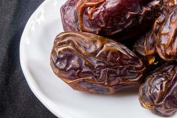 Big luxury dried date fruit in bowls on the dark surface, kurma ramadan kareem concept, close up.
