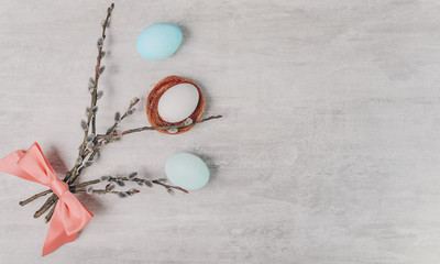 Easter white egg in nest and bouquet of willow branches on a grey table, rustic style