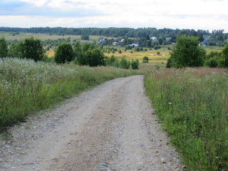 Fototapeta na wymiar Country road from a hill and a village in the distance