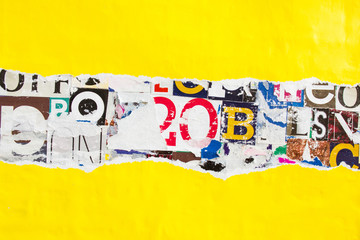 Torn and peeling yellow paper poster on colorful collage from clippings with letters and numbers texture background. Copy space for text message.