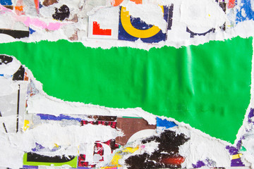 Green torn and crumpled piece of paper poster on dirty billboard texture background. Copy space for...