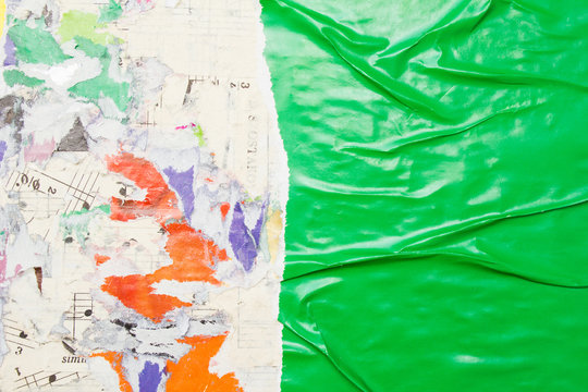 Torn and crumpled green glossy paper poster on billboard with old peeling pieces of paper placards texture background. Copy space for text.