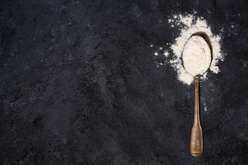 spoon with wheat flour on a black background