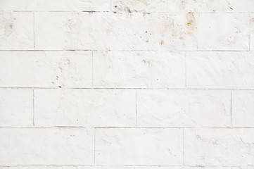 Naklejka premium Old white stone wall with dirty spots and stains and peeling paint texture background.