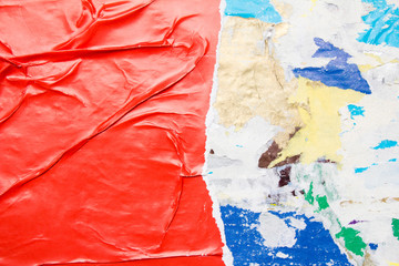 Red torn crumpled glossy paper poster on dirty billboard with old ripped placards texture...