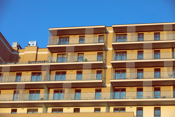 A high multi-family apartment block against a blue sky.