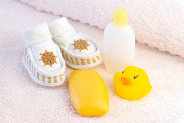 Fototapeta na wymiar baby hygiene and bath items, shampoo bottle, baby soap, towel, yellow duck rubber toy, cotton pads and ear sticks, comb.