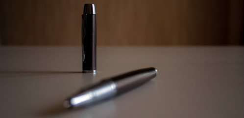 Cap and beautiful dark pen on grey office table. Concept.