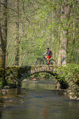 pretty mid age woman riding her mountainbike at a little river on a warm sunny spring day