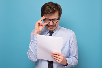 Serious successful caucasian man in glasses dressed elegnatly, reading documentation