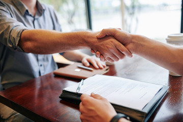 Close-up image of business people shaking hands after signing contract