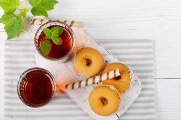 Two cups of hot tea with delicious cookies on white wooden table