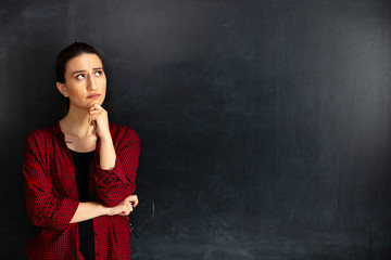 Young woman teacher thinking on blackboard.