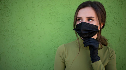 Beautiful young woman in protective medical mask and medical black gloves smiling eyes. Street portrait on isolated background.