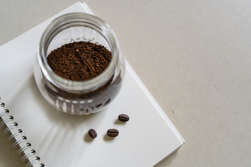 A jar of Ground coffee on notebook