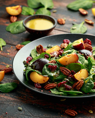 Vegan plums salad with cranberry, pumpkin seed, pecans nuts, spinach and mustard dressing
